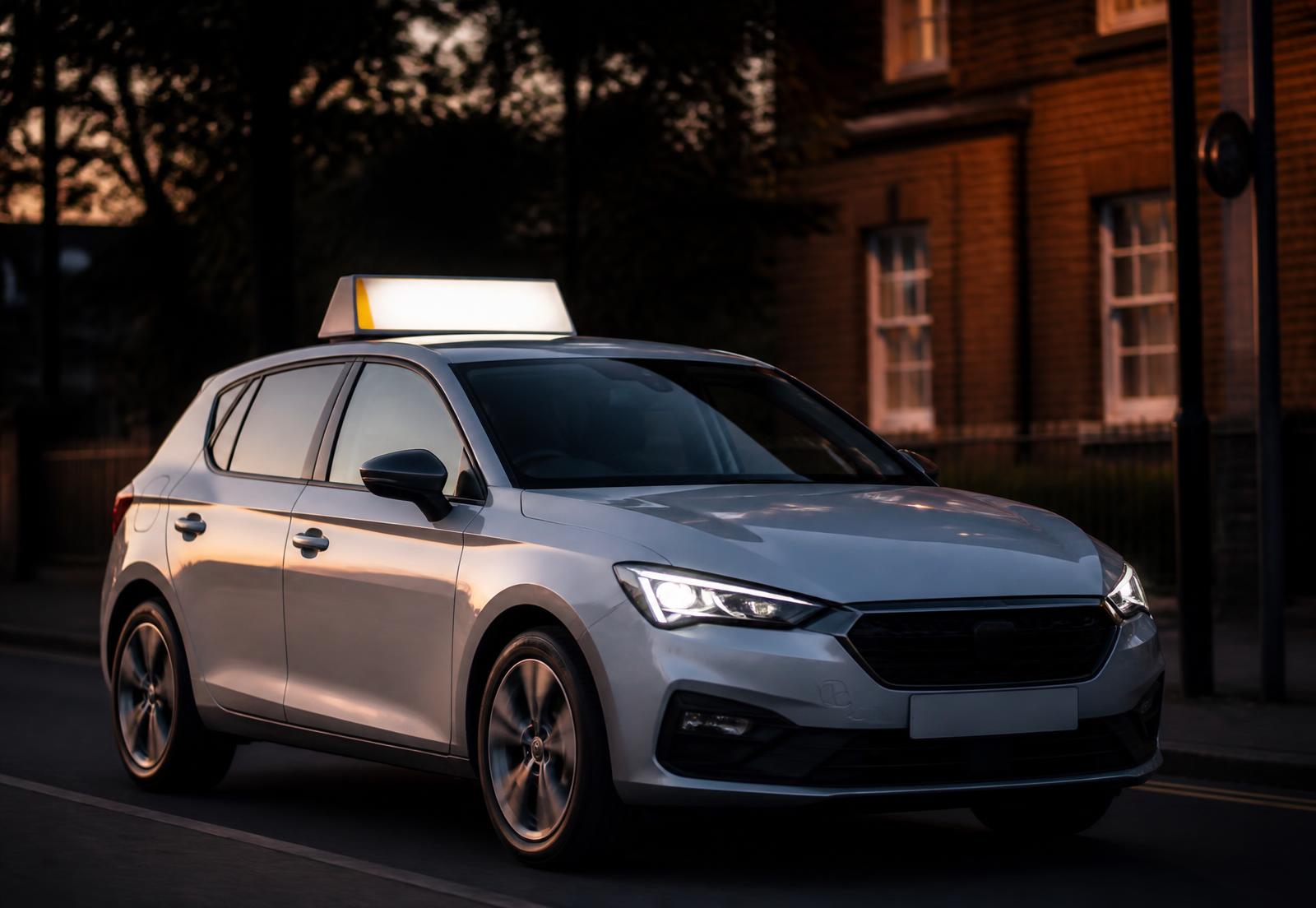Driving school car fitted with a professional illuminated roof sign at dusk